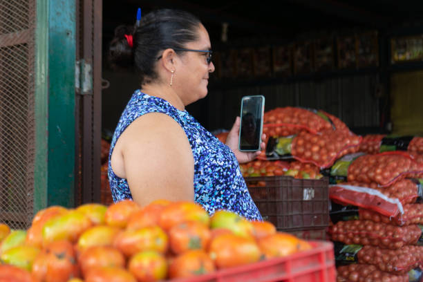 Managua, Nicaragua, november 5th 2021: Poor woman selling products online with her smartphone in a market of the city.