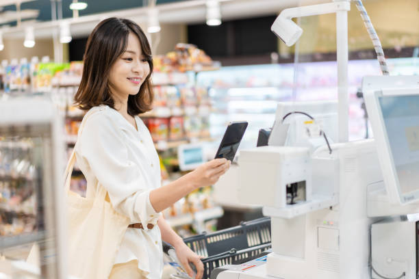 셀프 체크아웃 과 전자 돈을 지불 하는 젊은 여자 - retail paying checkout counter cash register 뉴스 사진 이미지