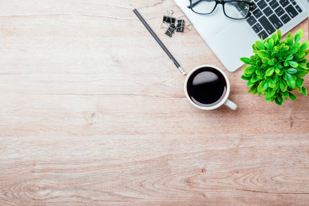 istock Work from home. desk office with laptop, blank notepad, coffee cup and pen on wood table. Flat lay top view copy spce. 1351772839