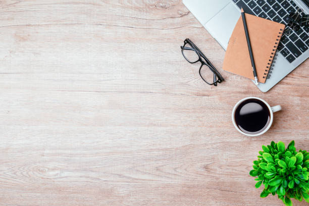 istock Work from home. desk office with laptop, blank notepad, coffee cup and pen on wood table. Flat lay top view copy spce. 1351772913
