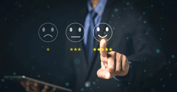 Photo of Customer Service and Satisfaction Concept Businessmen touch the virtual screen on happy smiley icons to achieve service satisfaction and feedback with excellent rated reviews.