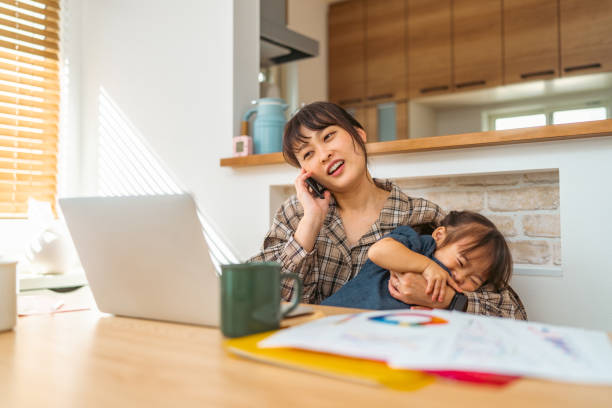 Mother trying to talk on phone while her small daughter interrupts her