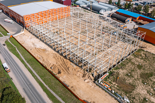 construction of new warehouse building in suburb area. steel frame construction. aerial view from the drone.