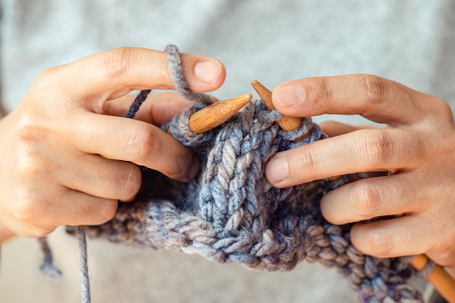Female hands hold knitting needles and knit a sock. Handmade and hobby concept. Close-up.