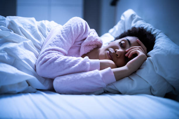 不眠症のベッドで目を覚ますアフリカ系アメリカ人の女性 ストックフォト