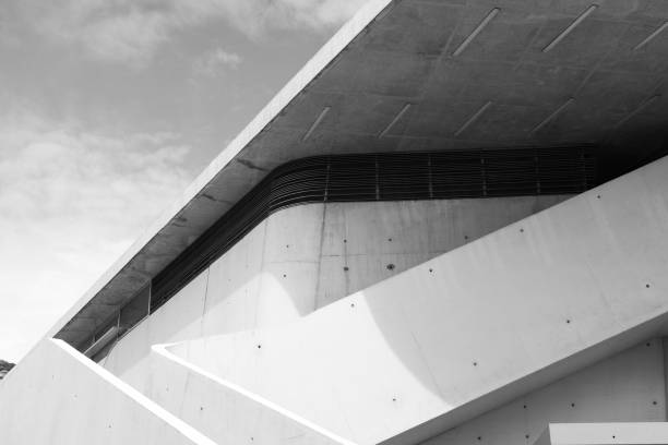 An exterior of a 1970s brutalist structure, with pebbledash render, air vents and white tiled surfaces.