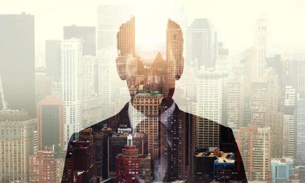 Photo of Portrait of a stylish young businessman dressed in a suit superimposed over a cityscape
