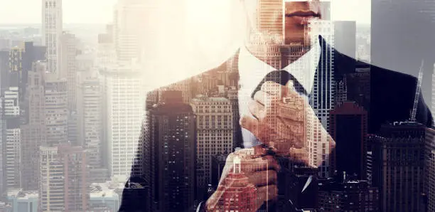 Photo of Cropped shot of a stylish young businessman dressed in a suit superimposed over a cityscape