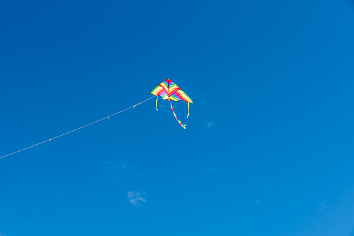 Colorful flying kite flying in blue sky with clouds