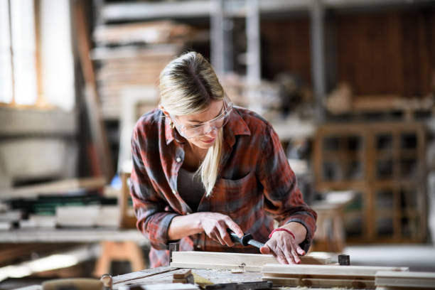 istock Female carpenter with goggles working on her product indoors in carpentry workshop. 1351795336