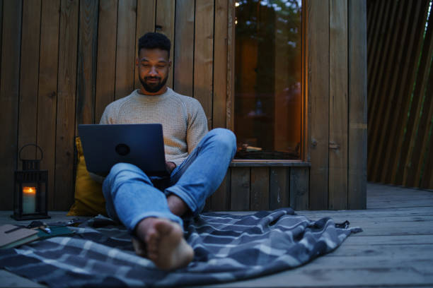 istock Happy young man with laptop resting outdoors in a tree house, weekend away and remote office concept 1351796606