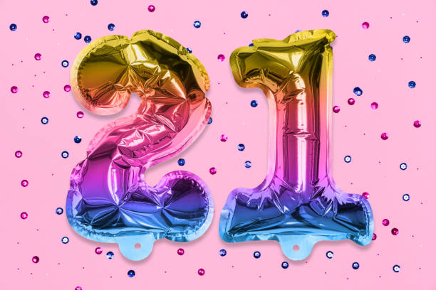 rainbow foil balloon number, digit twenty one on a pink background with sequins. birthday greeting card - 21e verjaardag stockfoto's en -beelden