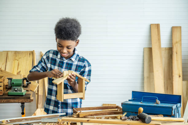 istock Smiling kid carpenter happy working with wood and sandpaper 1351797775