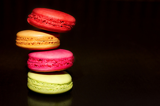 colorful almond baked goods on a dark background, photo for any purpose. Place for your text. culinary and confectionery factory concept. macaroon