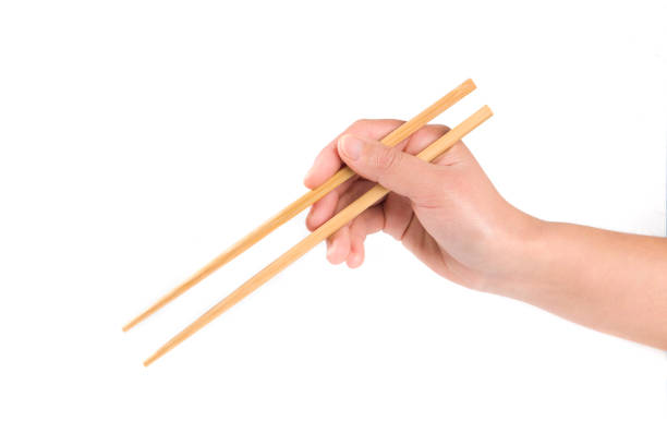 istock Person 's right hand using bamboo chopsticks against white background 1351801516