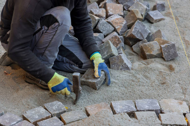 istock Road master in gloves lays paving stones in layers stone road by professional worker using stones and hammer 1351801567