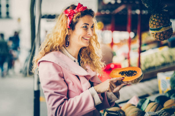 Nice woman buying papaya on market place in city stock photo