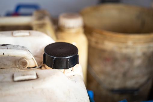 A plastic gallon of chemical or engine oil with black cap which is placed at factory chemical storage area. Industrial equipment object photo. Close-up and selective focus at the containment 's cap.