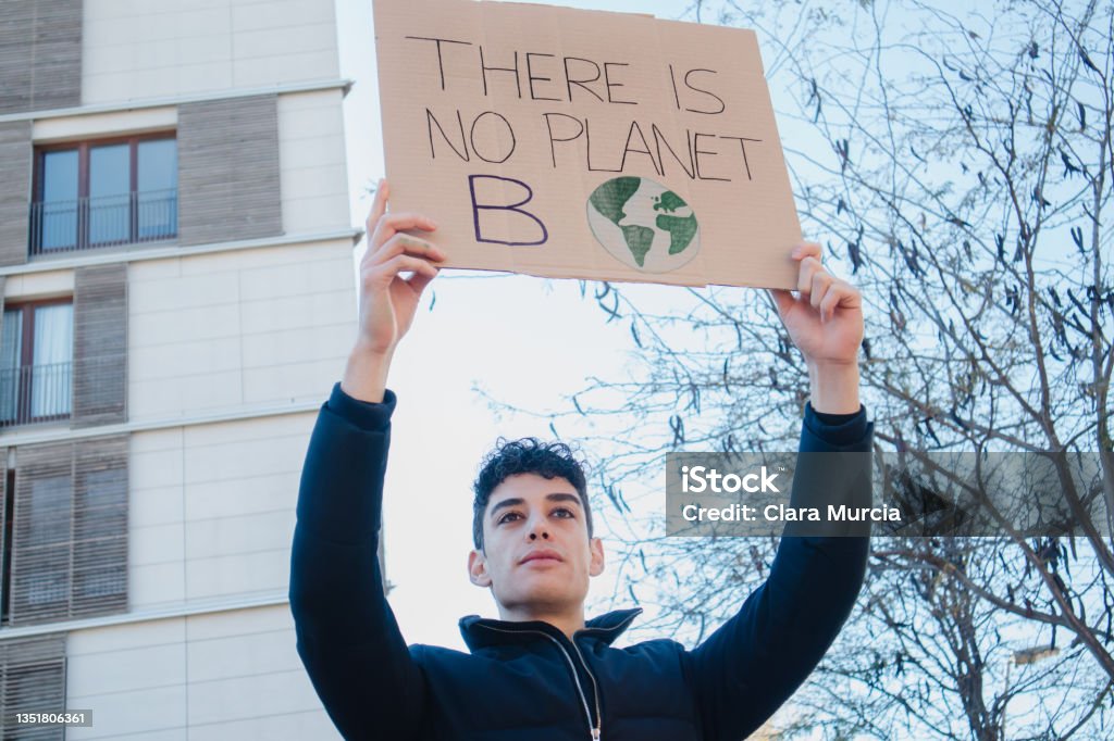 Arab teenager with climate change banner on environment demonstration Young man on climate summit demonstration 2021 United Nations Climate Change Conference Stock Photo