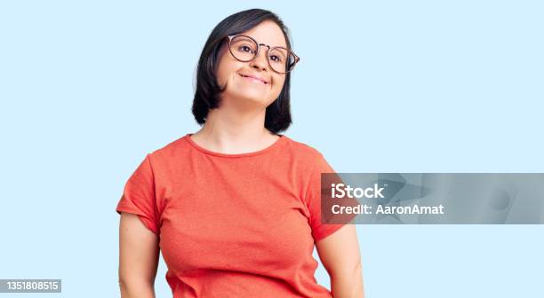 Brunette Woman With Down Syndrome Wearing Casual Clothes And Glasses Looking Positive And Happy Standing And Smiling With A Confident Smile Showing Teeth Stock Photo - Download Image Now