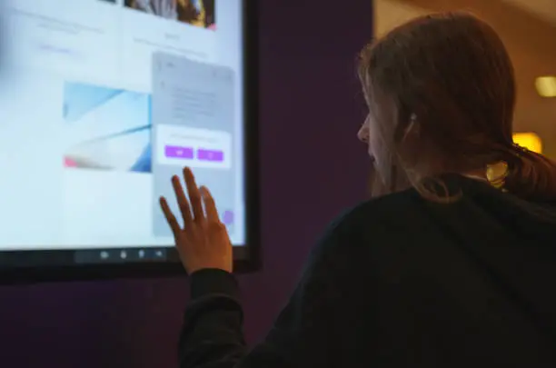 Teenage girl using touch screen display.