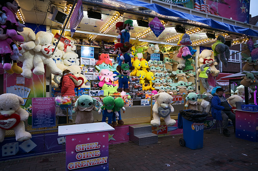 Molln, Germany, November 06, 2021: raffle ticket booth with oversized colorful plushies or stuffed toy animals and other prizes at the annual traveling fun fair, selected focus