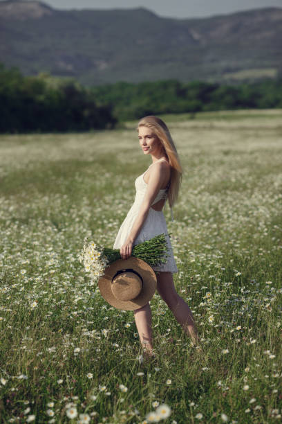 istock Beautiful woman enjoying daisy field 1351809813