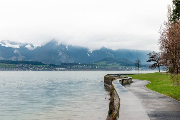 vista do lago thun e as montanhas envoltos em nuvens - thun - fotografias e filmes do acervo