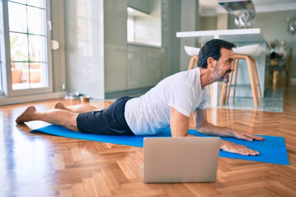istock Middle age man with beard training and stretching doing exercise at home looking at sport video on computer 1351810719