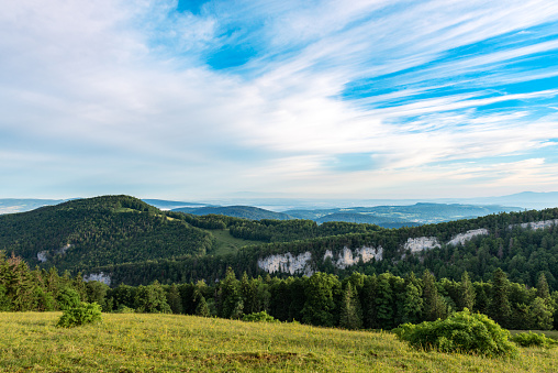 View over the mountain ranges and their grasslands and forests in the morning light. Far-reaching view at an altitude of over 1200 meters in the northern Jura Mountains of the canton of Solothurn. near the Passwang mountain pass