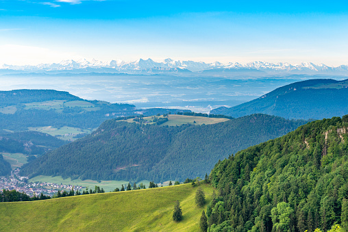 View over the mountain ranges and their grasslands and forests in the morning light. Far-reaching view at an altitude of over 1200 meters in the northern Jura Mountains of the canton of Solothurn. near the Passwang mountain pass