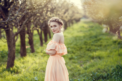 Beautiful young girl in an old dress in a pear-blossoming garden. Beautiful themed photography in retro style