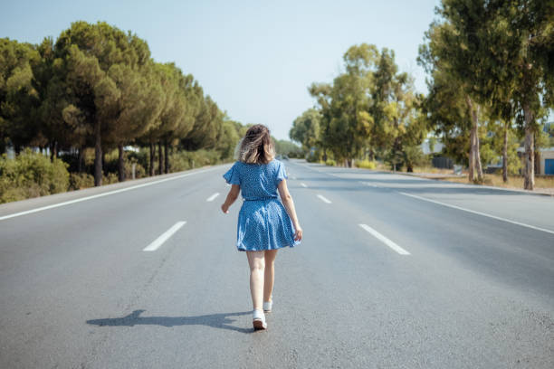 Young woman walking alone on the road. Horizontal composition.