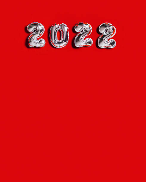 istock Silver balloons number 2022 New Year on red cloth background with copy space Layout for greeting card or invitation for new year party 1351812958