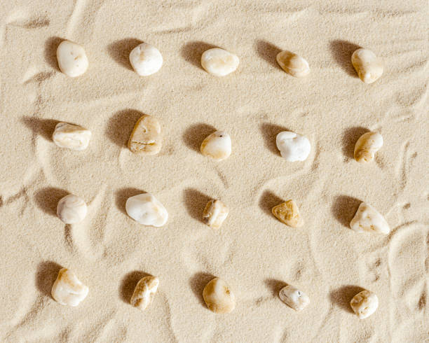 istock Pattern with white pebble sea stones on fine sand. Square composition from natural stone neutral beige color, monochrome tones. Spa minimal background 1351812973