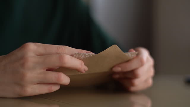 Attractive young woman opening envelope with letter, reading it and begins to feel happy at home.