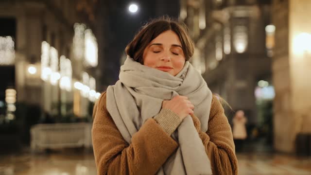 Woman covers her body with a scarf and close her eyes. Woman wearing warm clothing. Steadicam shot