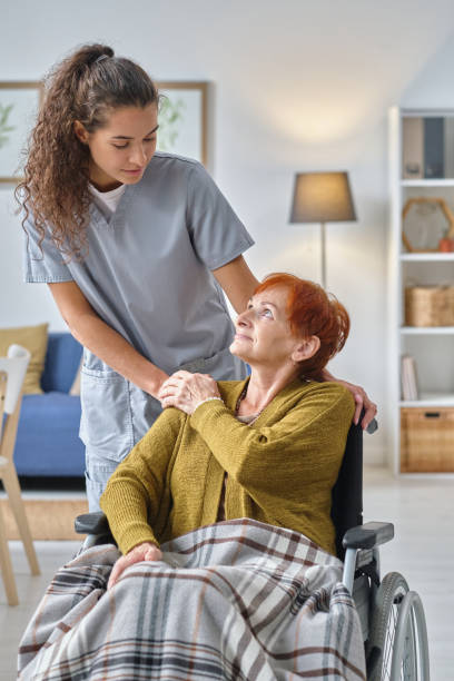 Nurse caring about senior woman Young nurse talking to senior woman who using wheelchair, she caring about her in nursing home home carer stock pictures, royalty-free photos & images