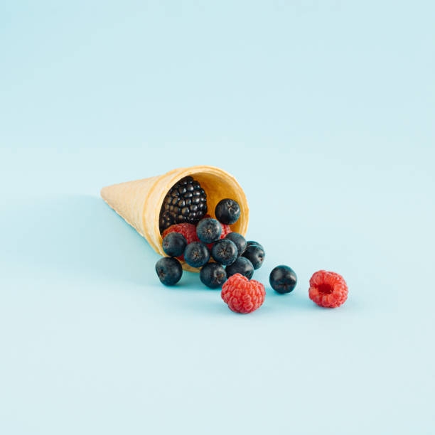 Creative idea of ice cream with  berry fruits in a cone on blue background. Minimal summer or healty dessert concept.