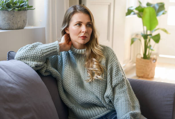 istock attractive middle aged woman sitting on the couch 1351822204
