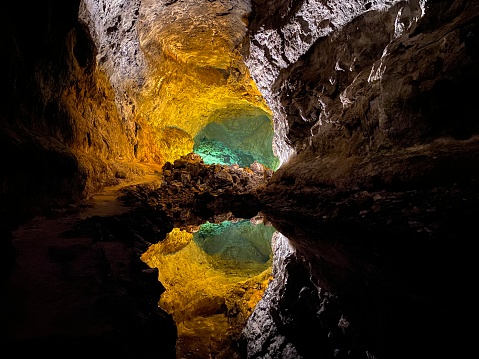 Various stalactites in an underground cave illuminated by a lamp.