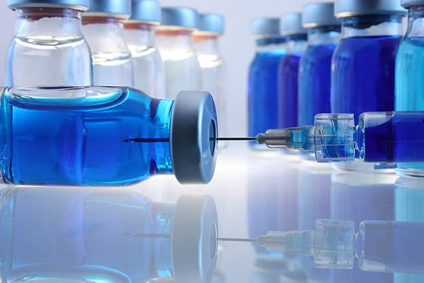 Laboratory bottles with blue content and a syringe