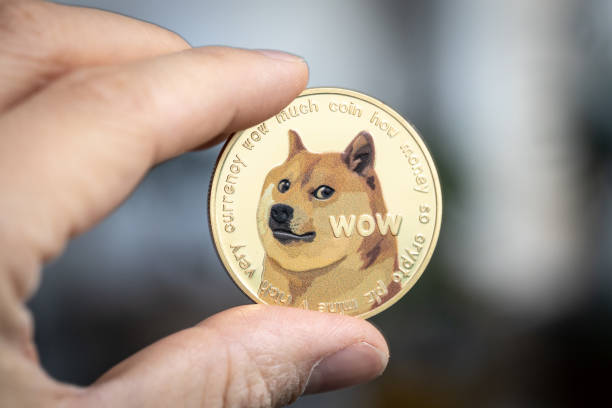 Dogecoin cryptocurrency physical coin held between two fingers. Dogecoin cryptocurrency physical coin held between two fingers. token photos stock pictures, royalty-free photos & images
