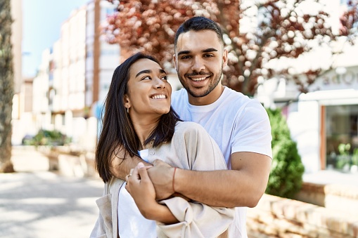 Young latin couple smiling happy and hugging at the city.