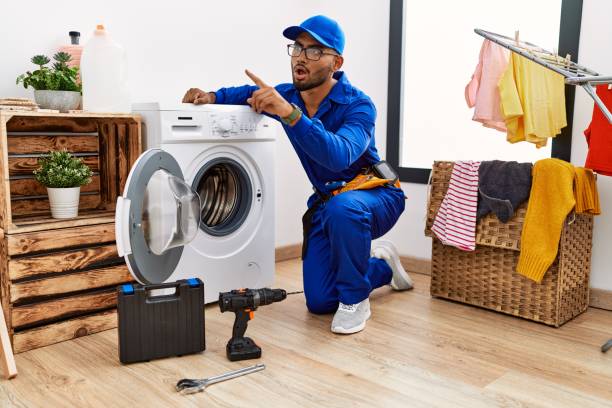 istock Young indian technician working on washing machine pointing with finger surprised ahead, open mouth amazed expression, something on the front 1351827167
