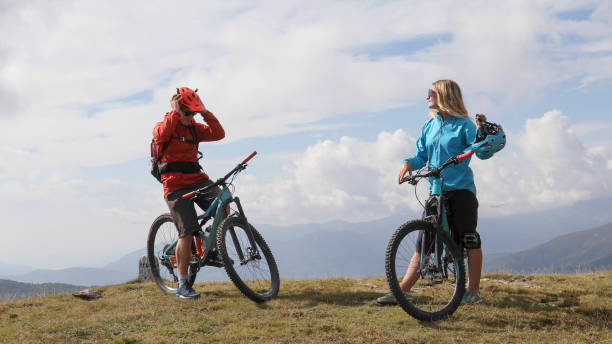 istock Mountain bikers relax on grassy mountain ridge 1351829289
