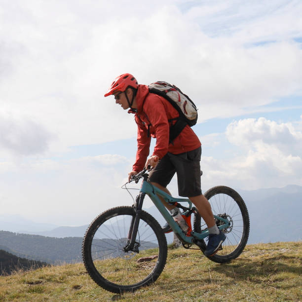 istock Young man mountain bikes on grassy mountain ridge 1351829307