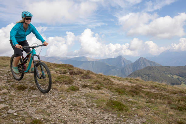 istock Young woman mountain bikes along mountain ridge 1351829386
