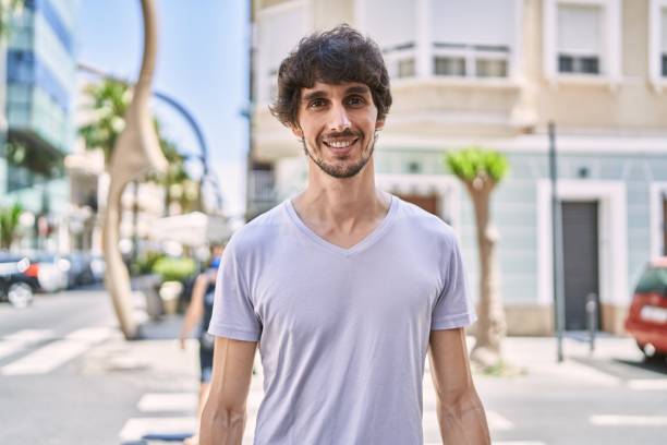 istock Young hispanic man smiling happy standing at the city. 1351831597