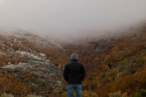 Portrait of adult man in black winter jacket against autumn color trees on mountain, in Tejera Negra, Cantalojas, Guadalajara, Spain